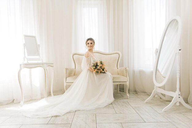 Portrait of a beautiful young bride in a bright room in a romantic atmosphere Bride with a bouquet of flowers