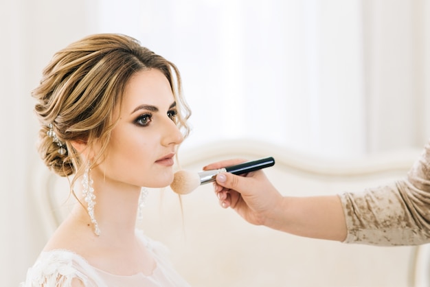 Photo portrait of a beautiful young bride in a bright room in a romantic atmosphere. brides perform makeup