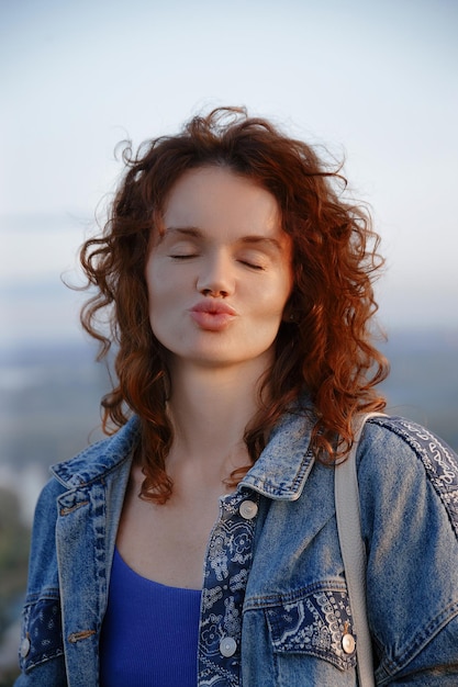 Foto ritratto di una bella giovane brunetta in abiti denim che soffia un bacio