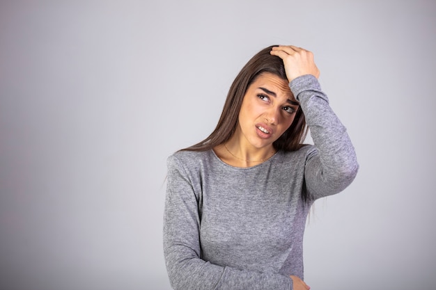 Foto ritratto di giovane e bella bruna toccando le tempie sensazione di stress, su sfondo grigio.