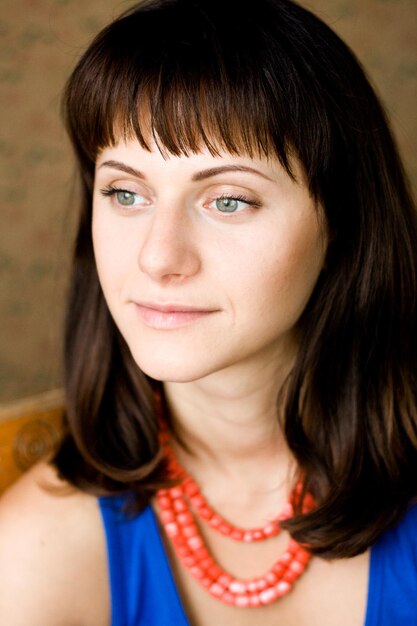 Portrait of a beautiful young brunette with red beads