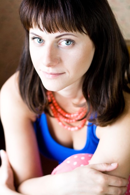 Portrait of a beautiful young brunette with red beads