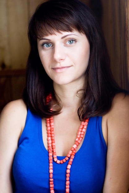 Portrait of a beautiful young brunette with red beads