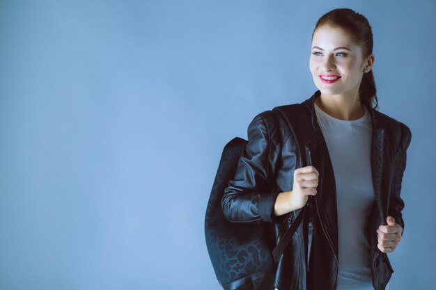 Portrait of beautiful young brunette woman in stylish black jacket on gray