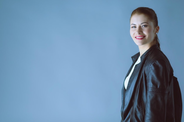 Portrait of beautiful young brunette woman in stylish black jacket on gray