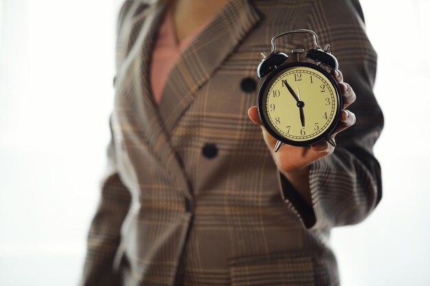 Portrait of beautiful young business woman holding in hands clock white background discipline and punctual concept