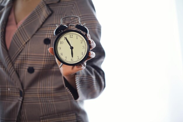 Photo portrait of beautiful young business woman holding in hands clock white background discipline and punctual concept