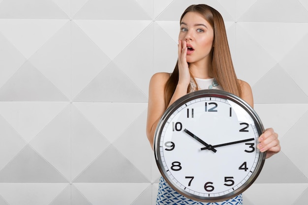 Portrait of beautiful young business woman holding in hands clock