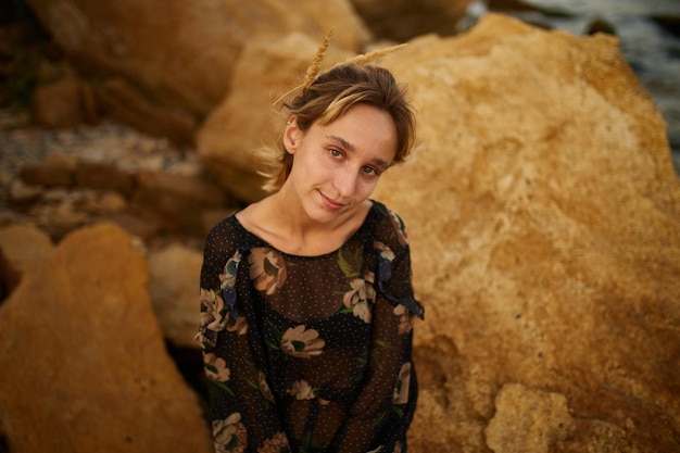 Portrait of a beautiful young Caucasian girl in a dress on the rocks by the sea in a dress close up