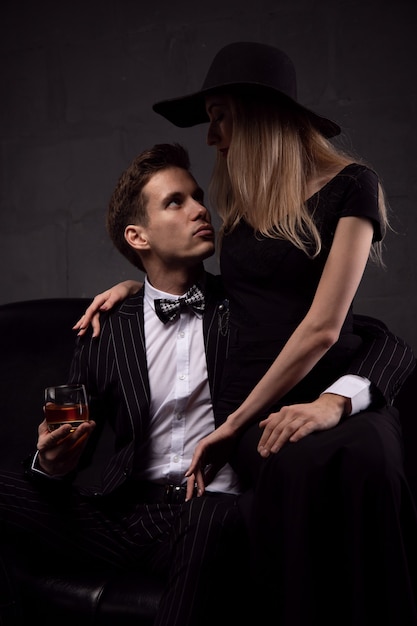 Portrait of a beautiful young couple in love, posing in a studio, dressed in classic clothes