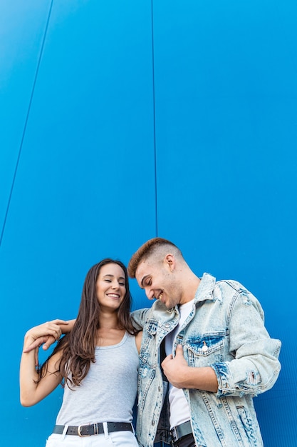 Portrait of a beautiful young couple in love smiling with blue wall and copy space