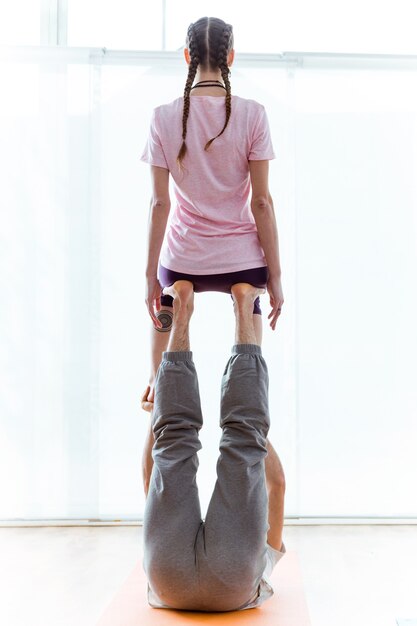 Foto ritratto di bella giovane coppia che pratica acro yoga a casa.