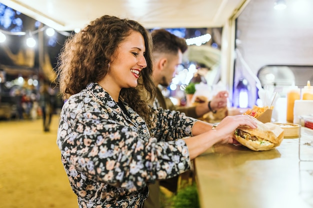 Photo portrait of beautiful young couple visiting eat market in the street.