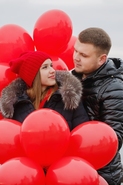 Портрет красивой молодой пары с красными воздушными шарами