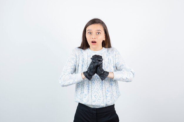 Portrait of beautiful young girl in black gloves standing and looking. 