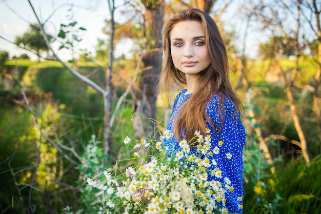 Portrait of a beautiful young girl in blue dress, outdoors, in the field