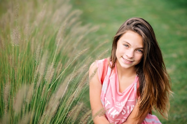 Portrait of a beautiful young girl in green summer grass.