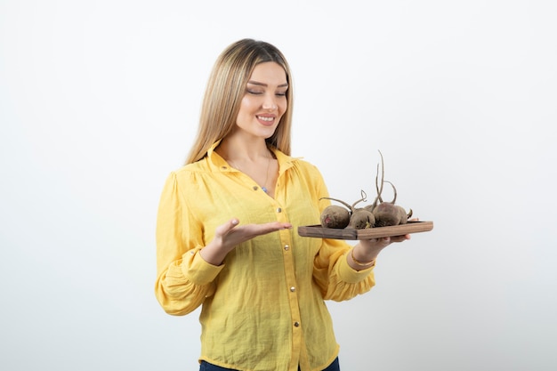 Portrait of beautiful young girl looking at beetroot over white