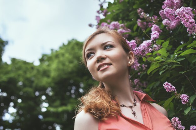 Portrait of a beautiful young girl in the park. lilac blossoms