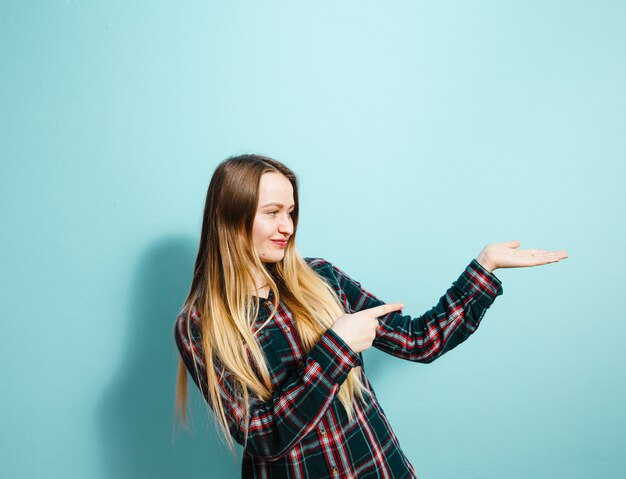 Портрет красивой молодой девушки, показывая жесты и счастлив на синем фоне