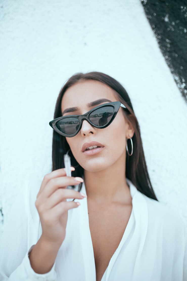 Photo portrait of a beautiful young girl smoking a cigarette against wall