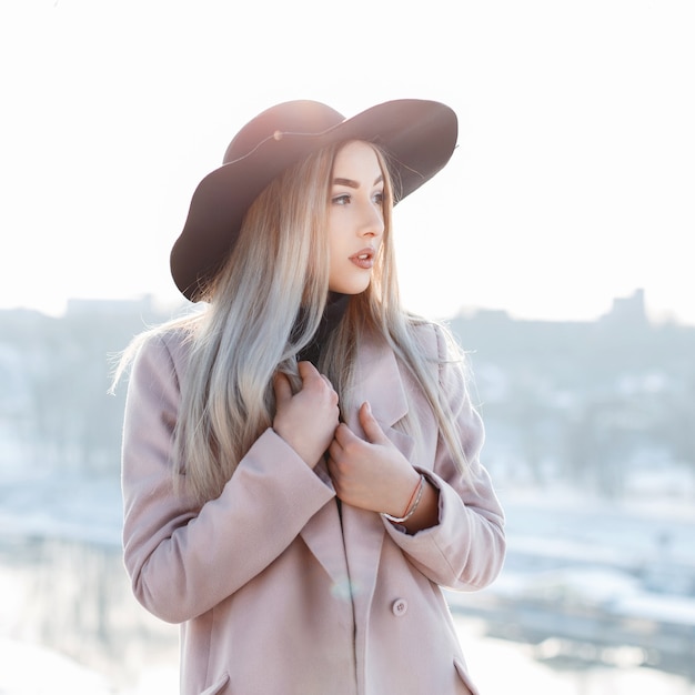 Portrait of a beautiful young girl in a stylish hat and coat on a sunny winter day