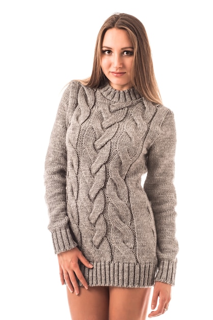 Portrait of a beautiful young girl wearing a knitted sweater posing in studio on a white wall