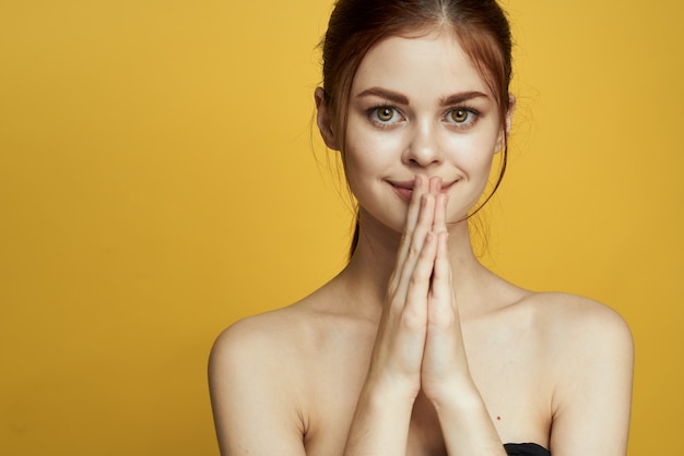 Portrait of a beautiful young girl with beautiful skin on a yellow background