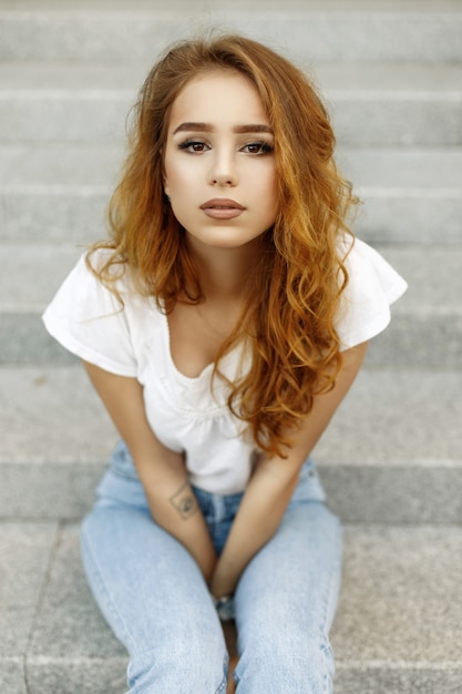 Portrait of a beautiful young girl with brown eyes and red hair on a light