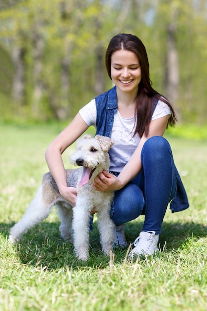 Портрет красивой молодой девушки с собакой фокстерьер на открытом воздухе в парке