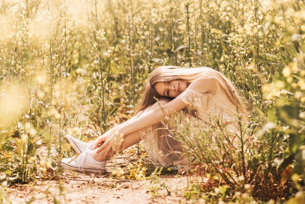 Foto ritratto di una bella ragazza con i capelli lunghi sullo sfondo di fiori di colza. giovinezza e natura