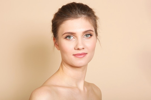 Portrait of a beautiful young girl with nude makeup on a colored background