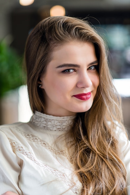 Portrait of beautiful young girl with professional makeup and hairstyle in restaurant.