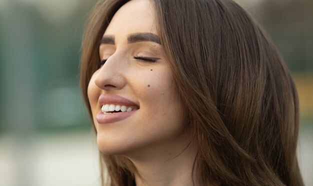 Portrait of beautiful young happy smiling woman, outdoors, with copy space.