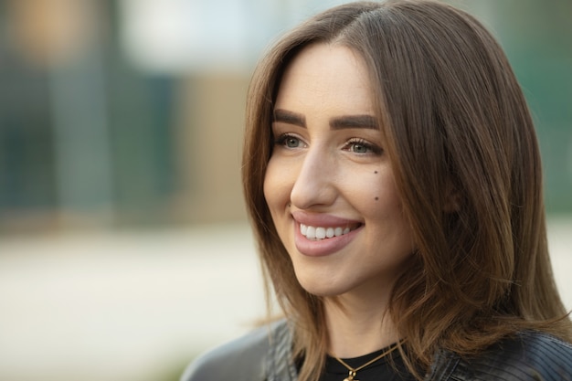 Photo portrait of beautiful young happy smiling woman, outdoors, with copy space.