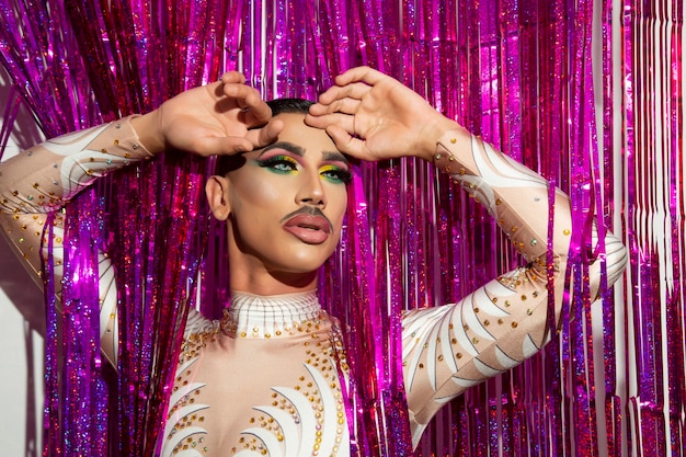 Portrait of beautiful young man in drag queen makeup and colorful background