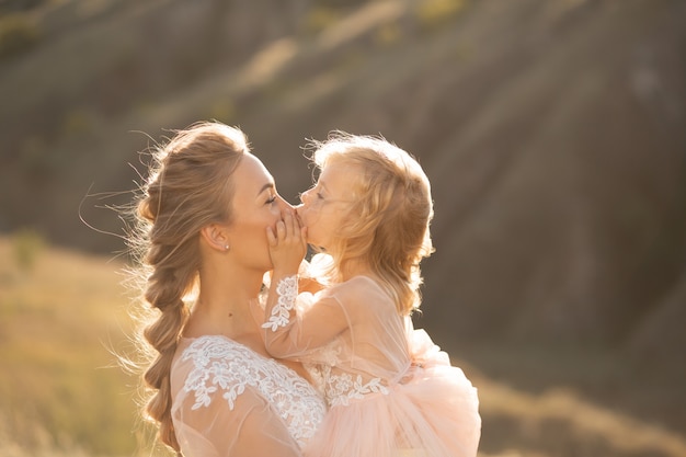 Portrait of a beautiful young mom holds her beloved daughter in her arms. Parental love, little princess