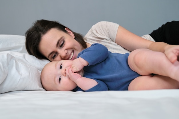 Portrait of beautiful young mother and her baby lying in bed together