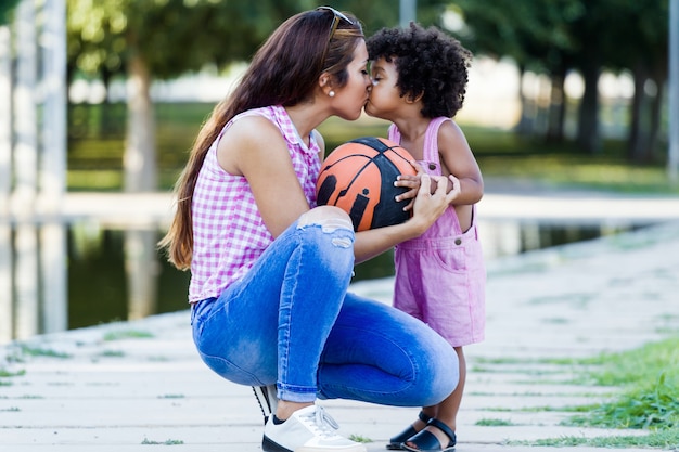 Portrait of beautiful young mother kissing her son in the park.