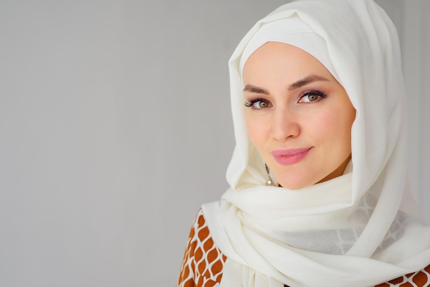 Portrait of beautiful young muslim arabian woman wearing white hijab looking at camera, copy space