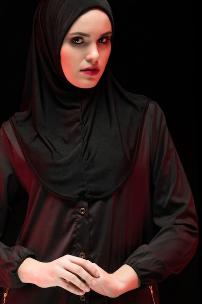 손에 손으로 보수적 인 패션 컨셉으로 검은 히잡을 입고 아름다운 젊은 무슬림 여성의 초상화