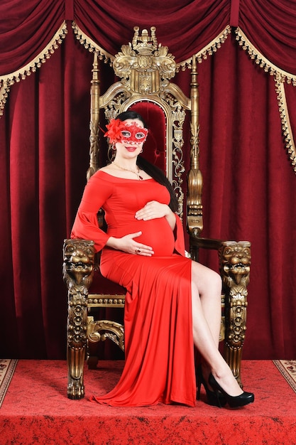 Портрет красивой молодой беременной женщины в маске позирует