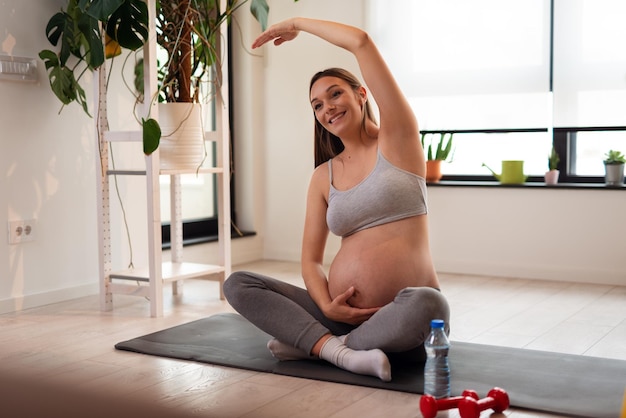 Ritratto di una bella giovane donna incinta seduta e fare yoga. allenamento, yoga e fitness