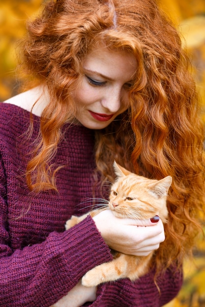 Photo portrait of a beautiful young red-haired woman holding a cat