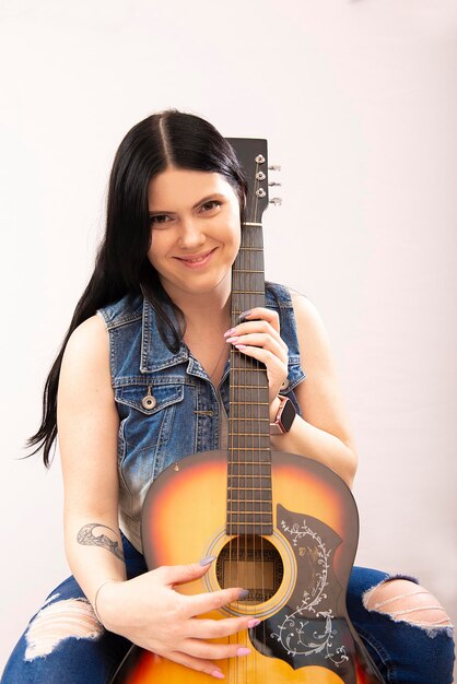 портрет красивой молодой сексуальной женщины с акустической гитарой на белом фоне