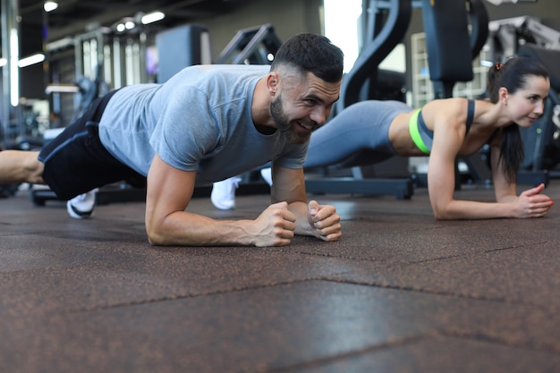 Portrait of beautiful young sports couple on a plank position.