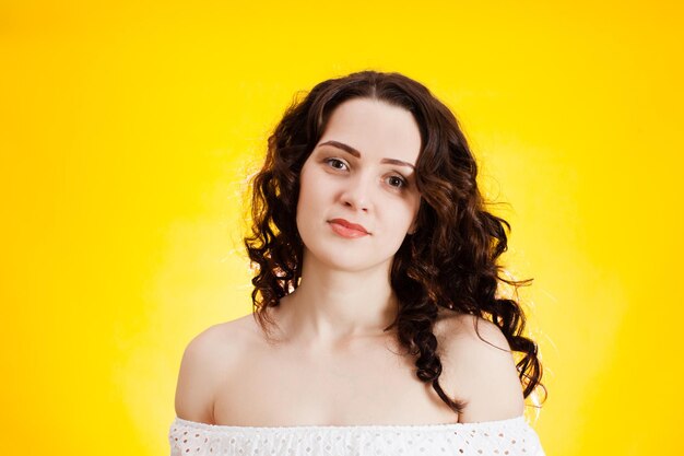 Portrait of beautiful young woman against yellow background