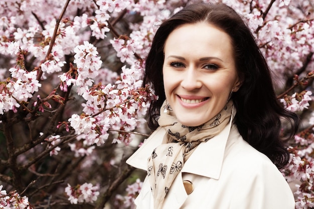 Portrait of a beautiful young woman on a background of pink cherry blossoms in spring