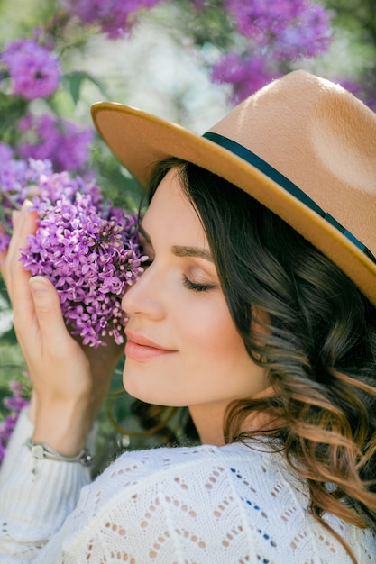 Portrait of a beautiful young woman in a blooming lilac park. 