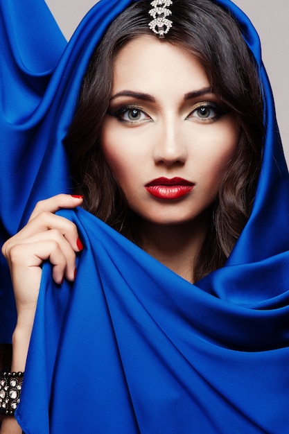 Portrait of a beautiful young woman in blue fabric